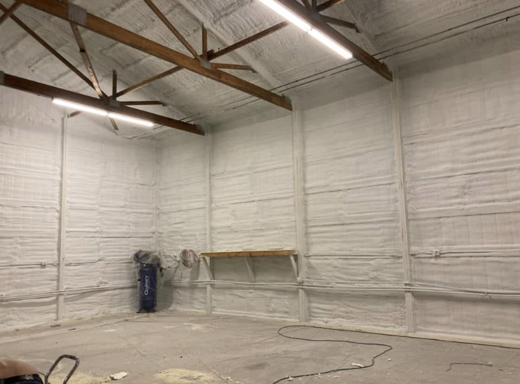 A large empty room with white walls and wooden beams.