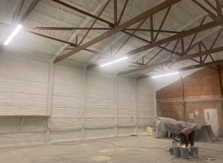 A man is spray painting the walls of a building.