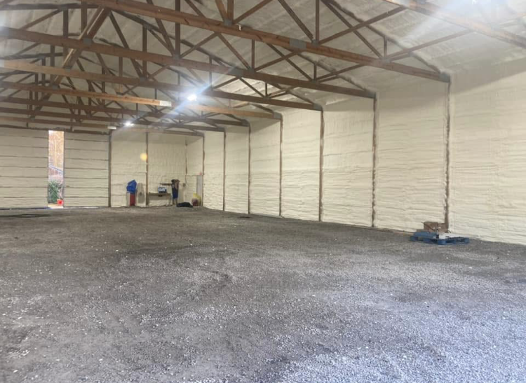 A large empty warehouse with a gravel floor and white walls.