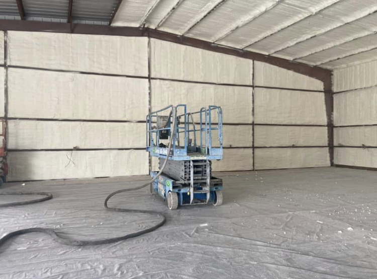A scissor lift is sitting inside of a large building.