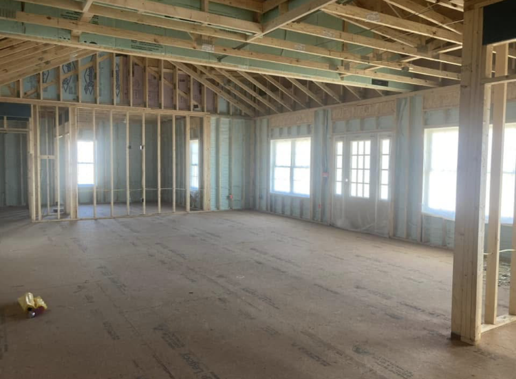 An empty room in a house under construction with a lot of windows.