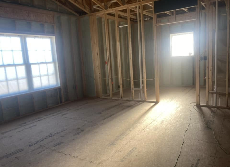 The sun is shining through the windows of a room under construction