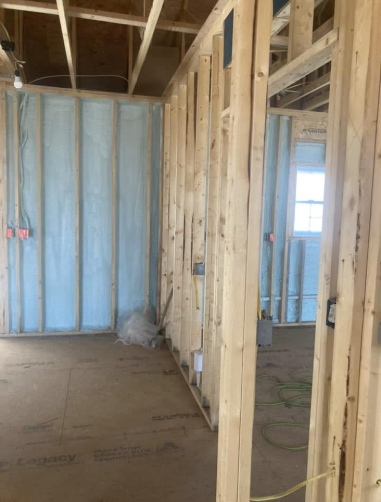 A room in a house under construction with wooden beams and insulation.