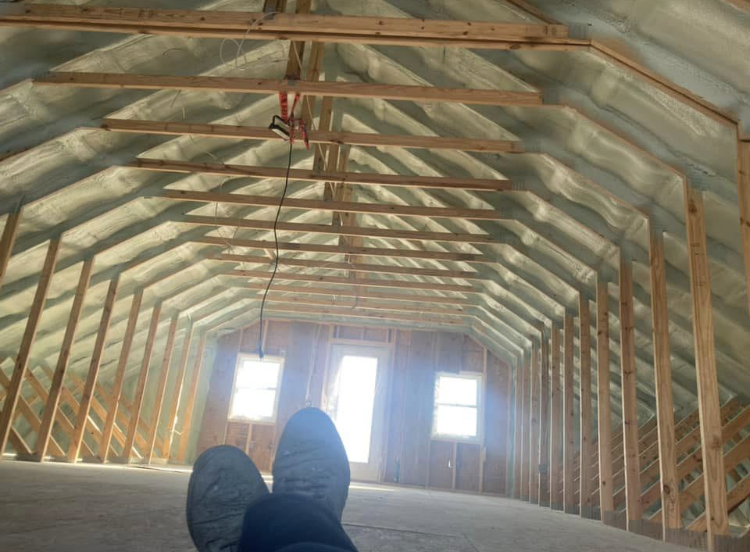 A person is laying in the attic of a house under construction.