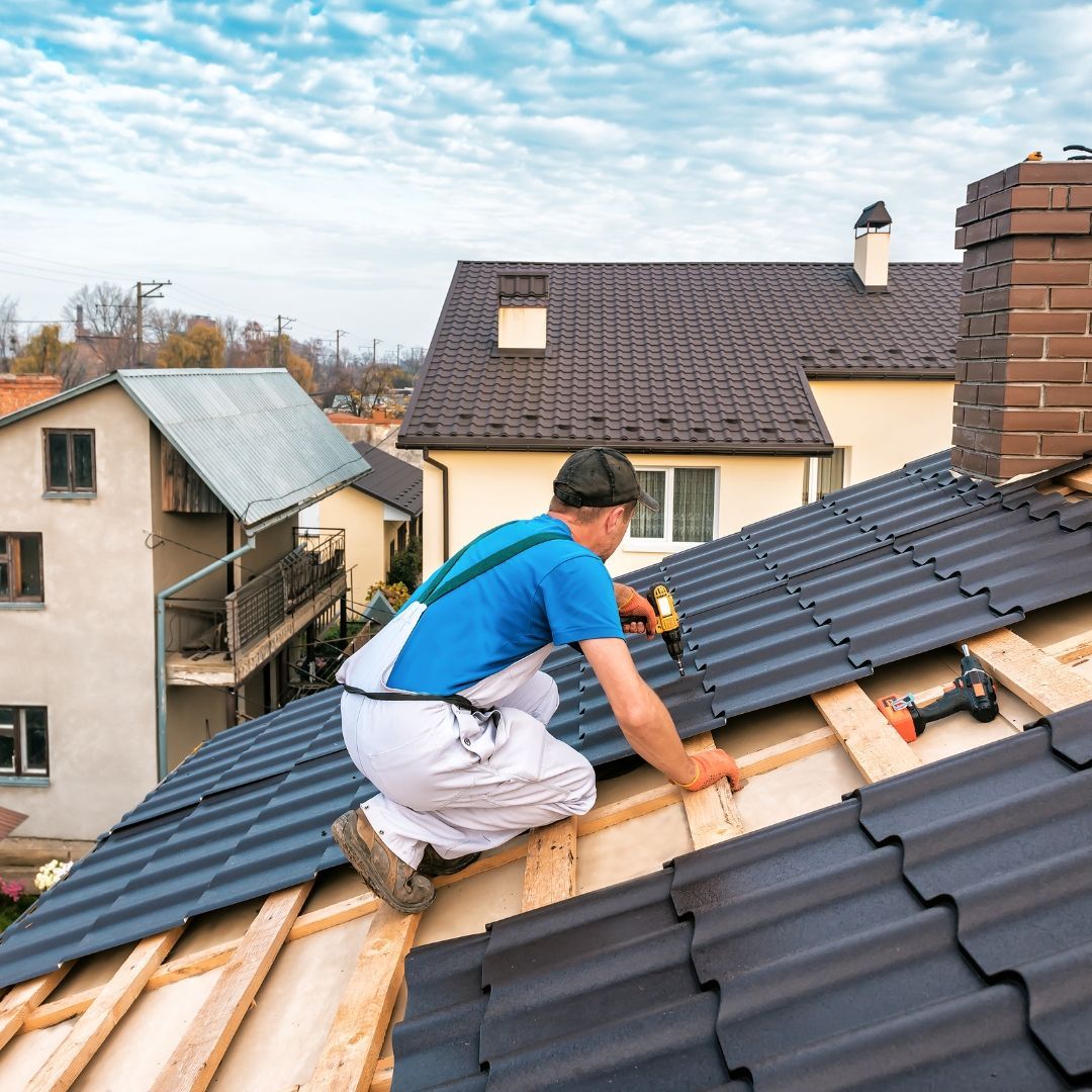 Hand cutting asphalt roofing shingle with utility knife during installation.