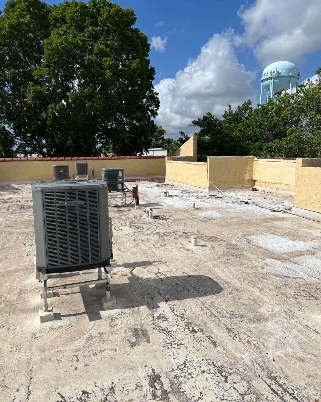 Rooftop with air conditioning units, concrete surface, yellow walls, and a blue domed structure in the background.