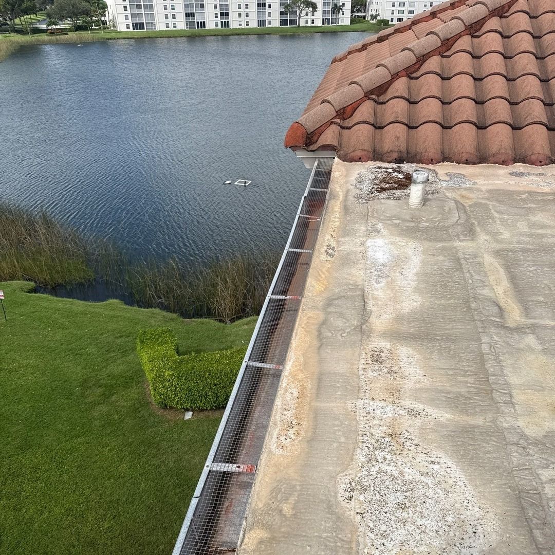 View from a roof with red tile edge, overlooking a lake and green grass.
