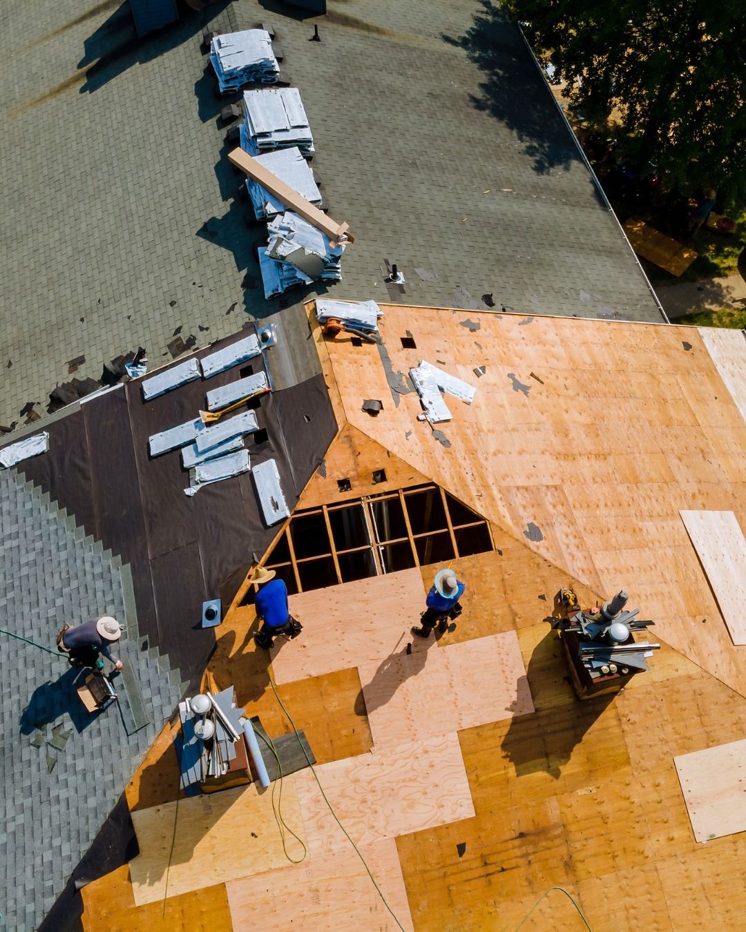 Roofing crew working on a house roof. Workers are installing new roofing materials on a sunny day.