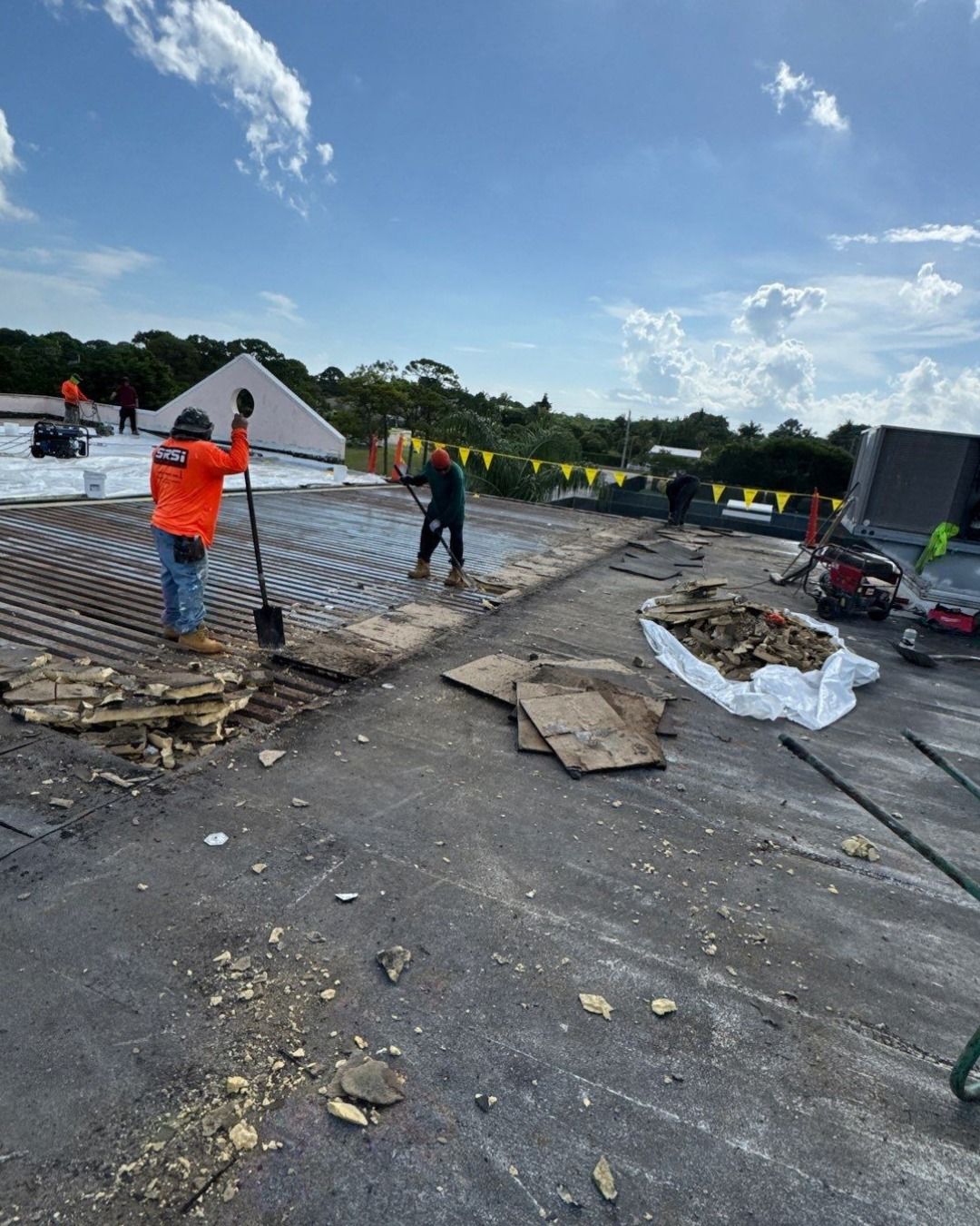 Construction workers repairing a flat roof on a sunny day.