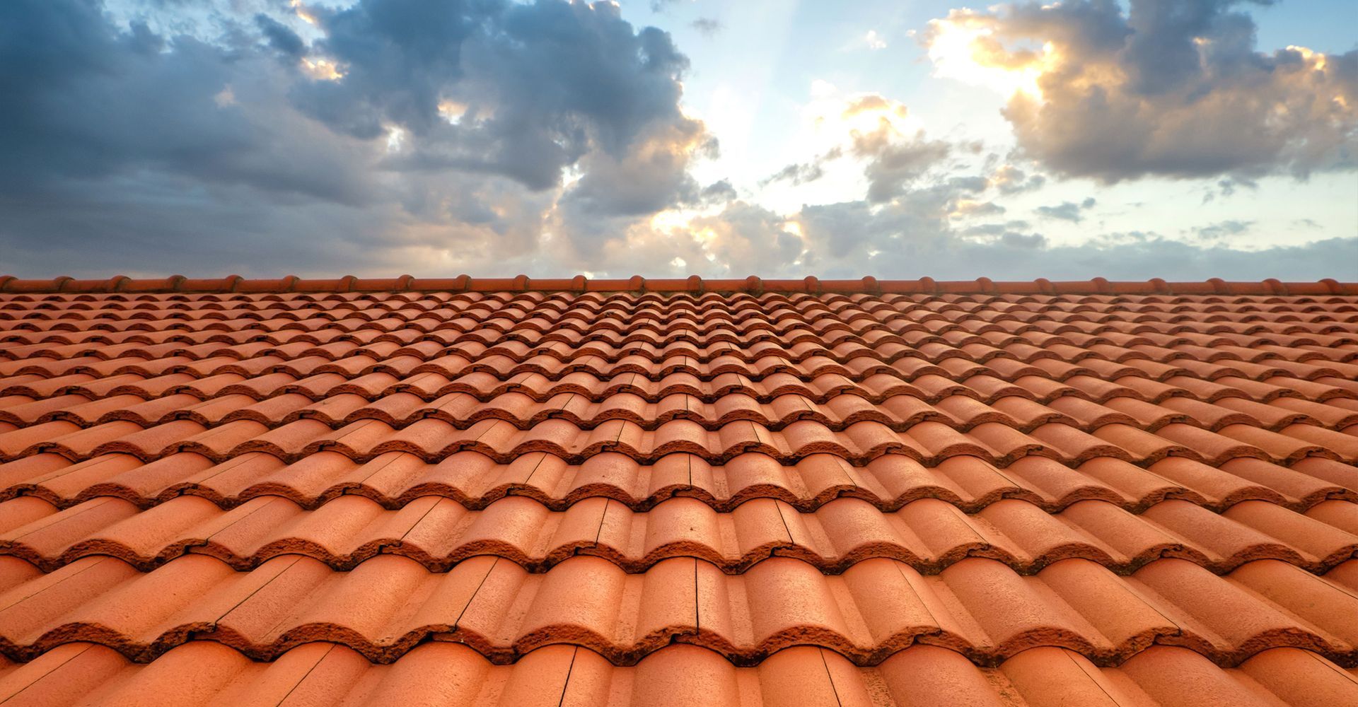 Clay tile roof under a cloudy sky.