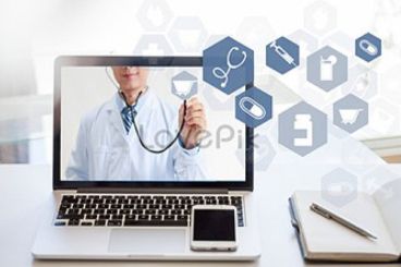 A doctor is holding a stethoscope in front of a laptop computer.