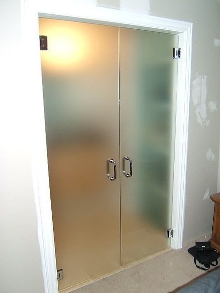 Frosted glass double closet doors with white trim in a hallway