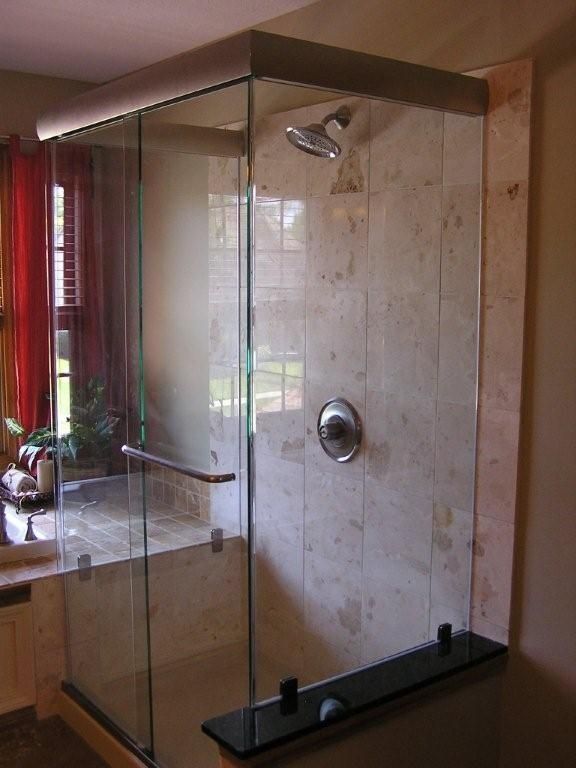 Modern glass shower enclosure with marble walls and chrome fixtures in a bathroom