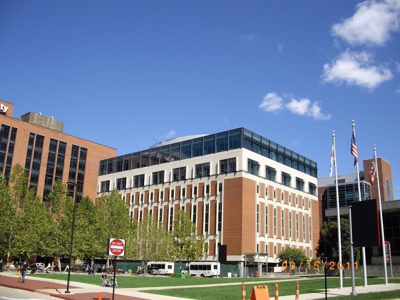 Brick office building with white trim, flags, and a blue sky on a city street
