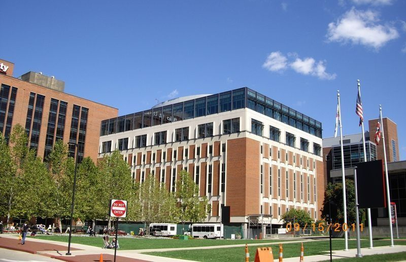 Brick office building with white trim, flags, and a blue sky on a city street