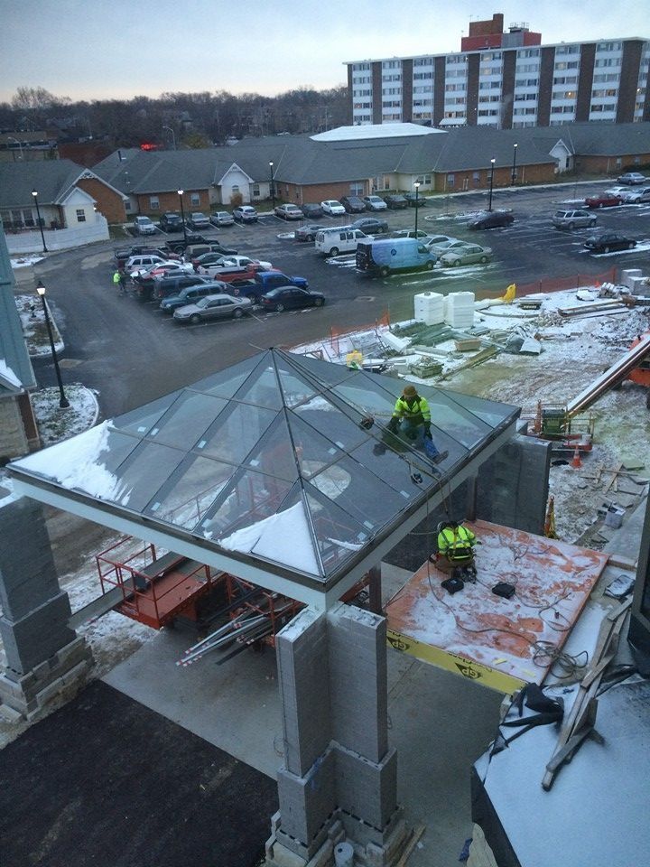 Workers installing a glass roof over an entrance at a snowy construction site