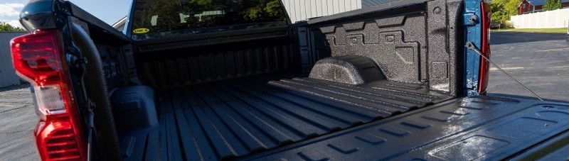 The back of a truck is empty and sitting on the side of the road.