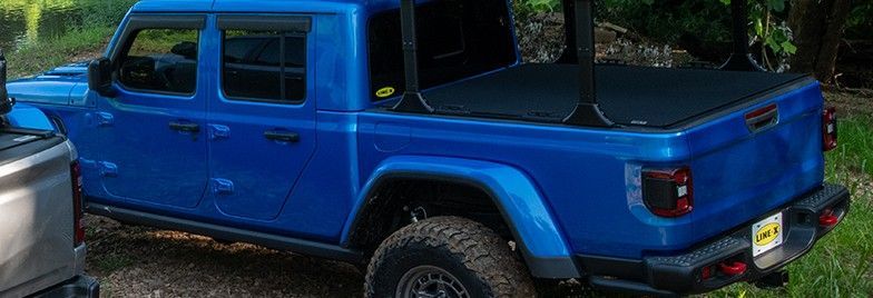 A blue jeep gladiator is parked next to a silver truck.