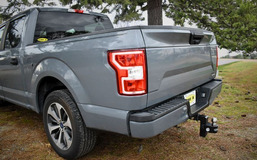 A gray ford f150 truck is parked in a grassy field.