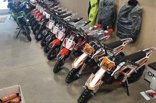 A row of dirt bikes are lined up in a garage.
