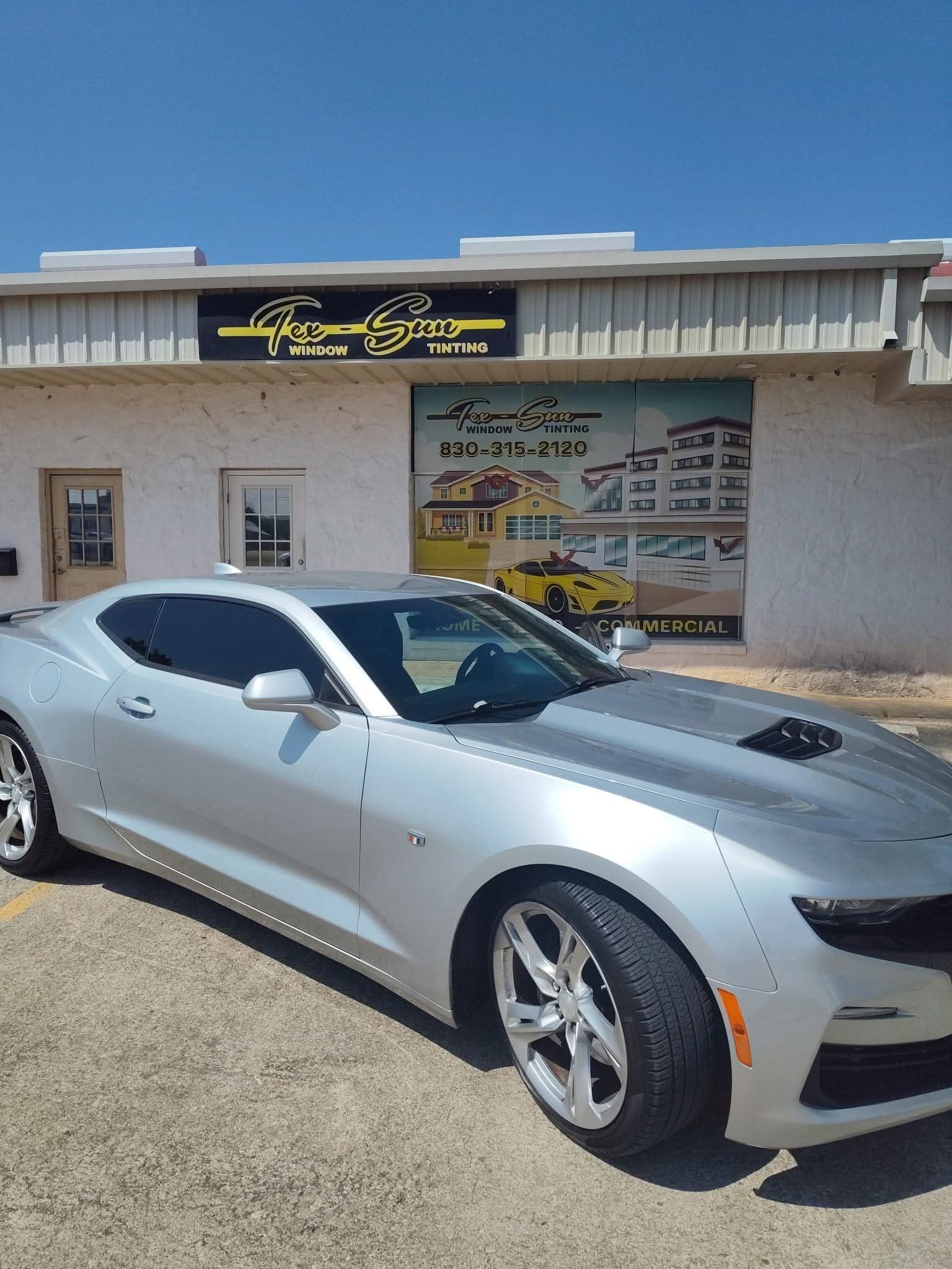 A silver car is parked in front of a building.