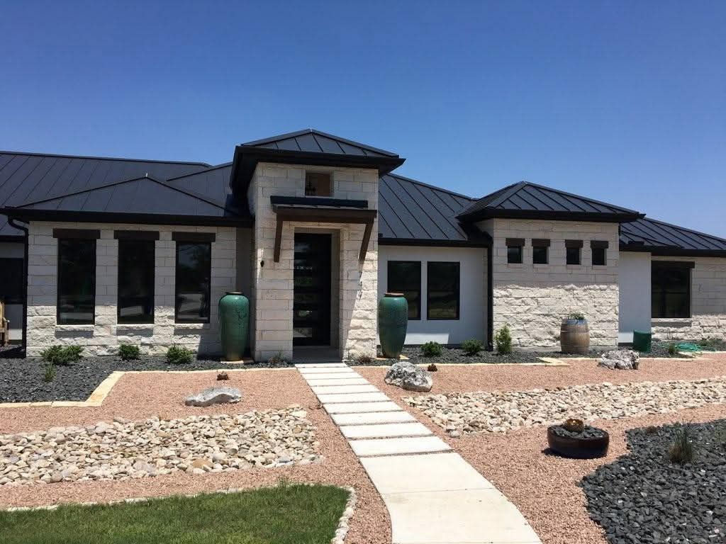 A large house with a black roof and a walkway leading to it.