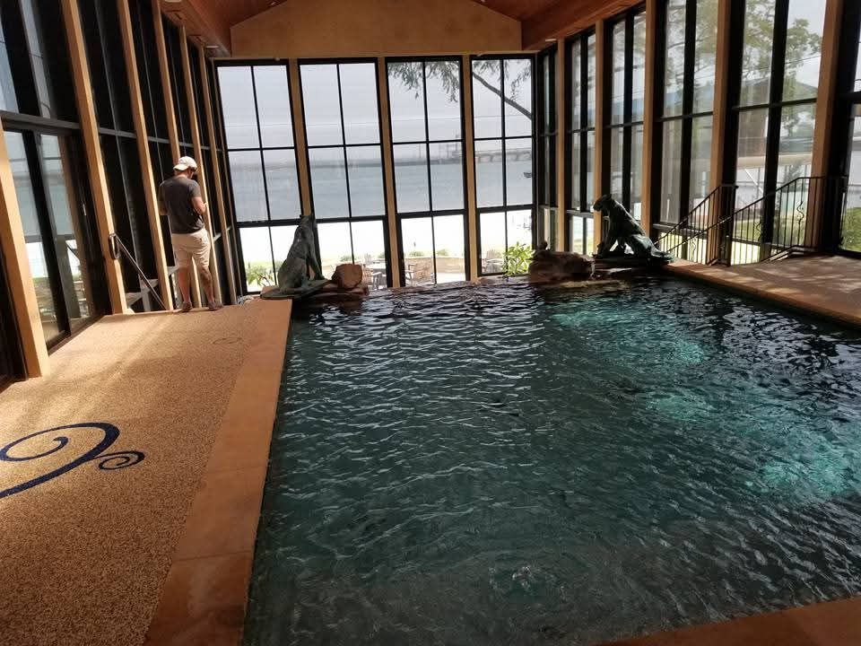 A man is standing next to a large indoor swimming pool.