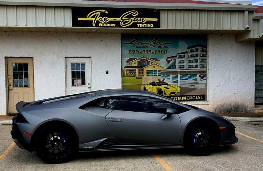 A gray sports car is parked in front of a building.