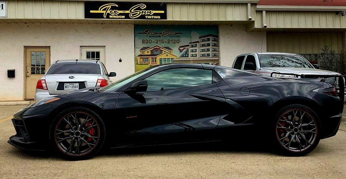 A black sports car is parked in front of a building.