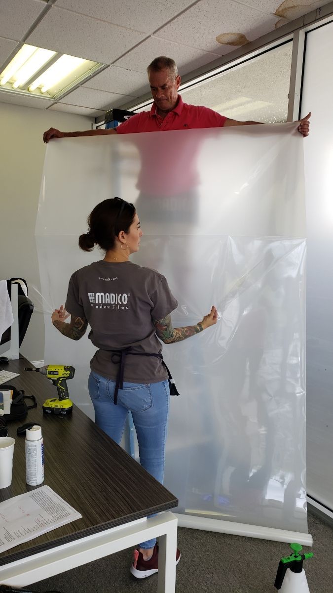 A man and a woman are holding a large piece of plastic in a room.