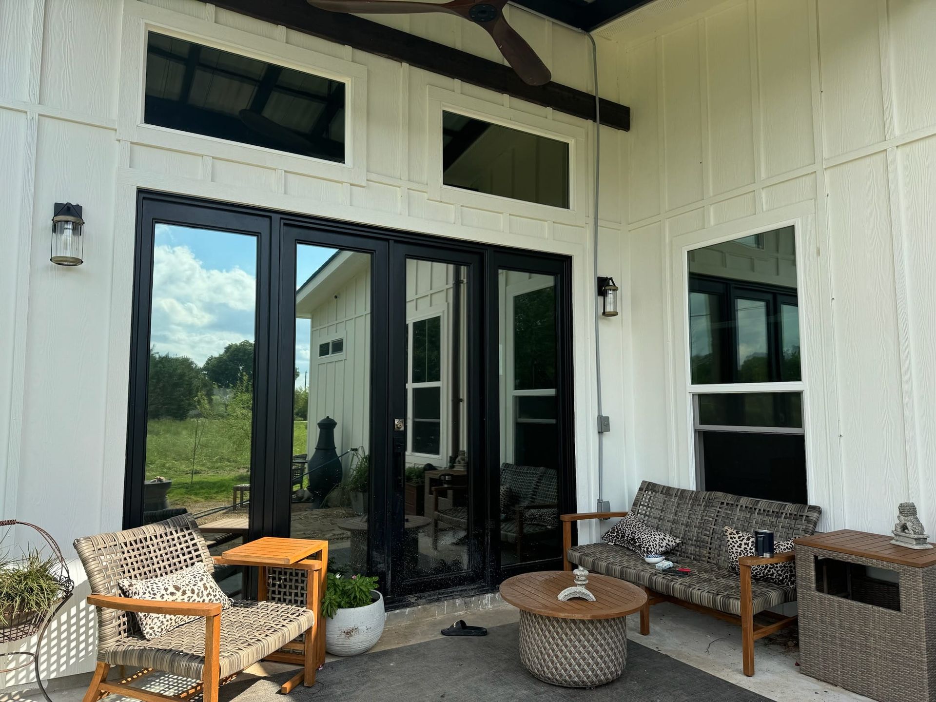 A patio with a couch , chairs , a table and a ceiling fan.