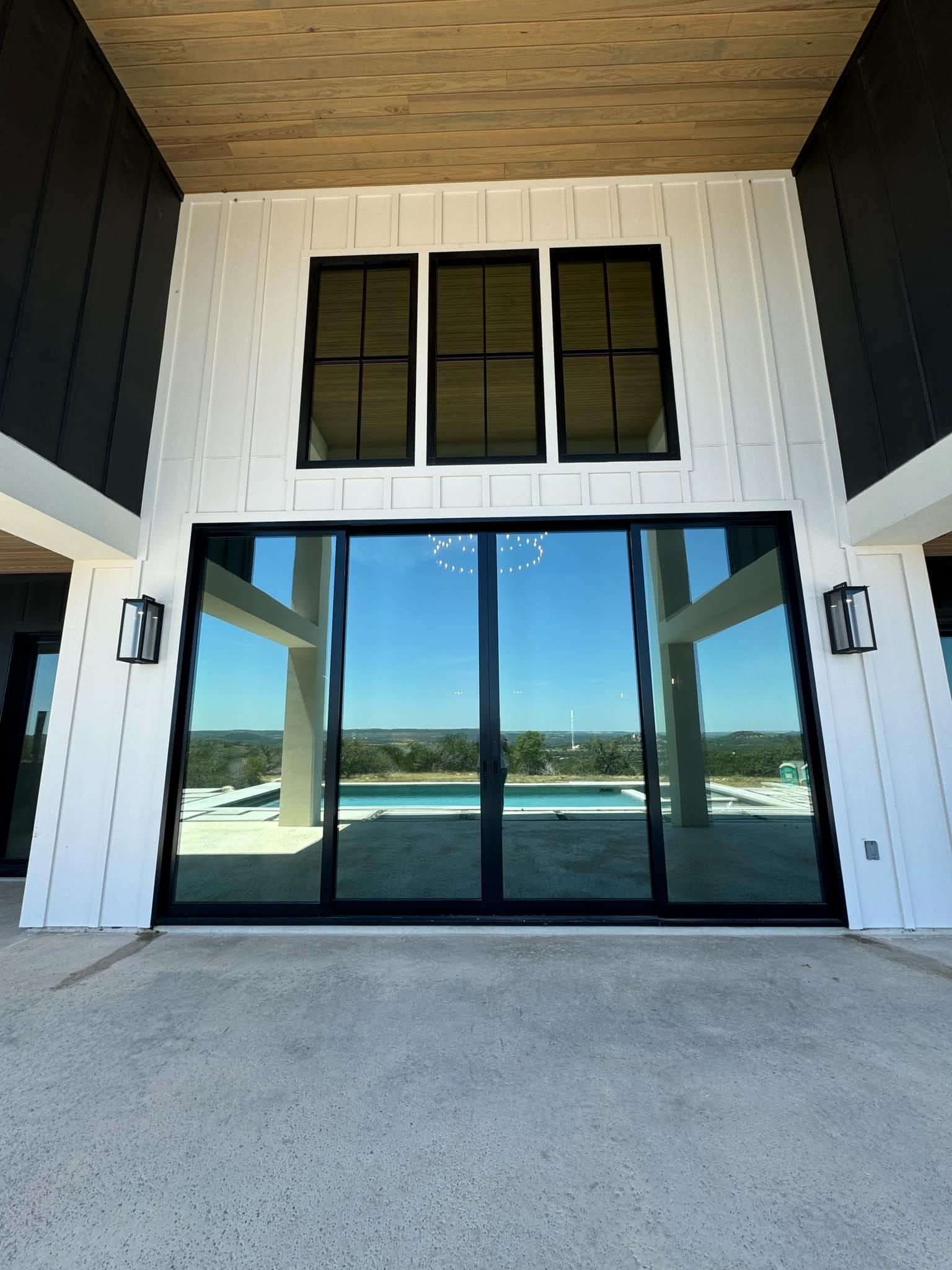 A large sliding glass door with a pool in the background