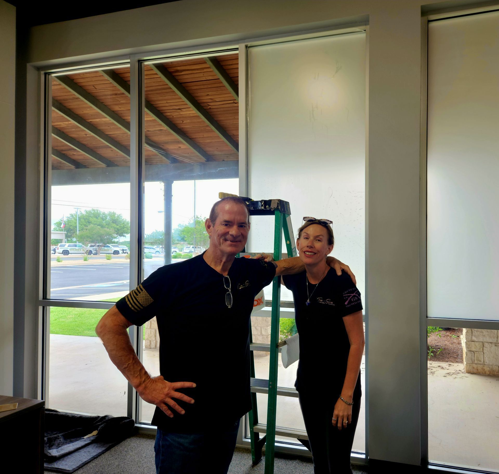 A man and a woman are posing for a picture in front of a window