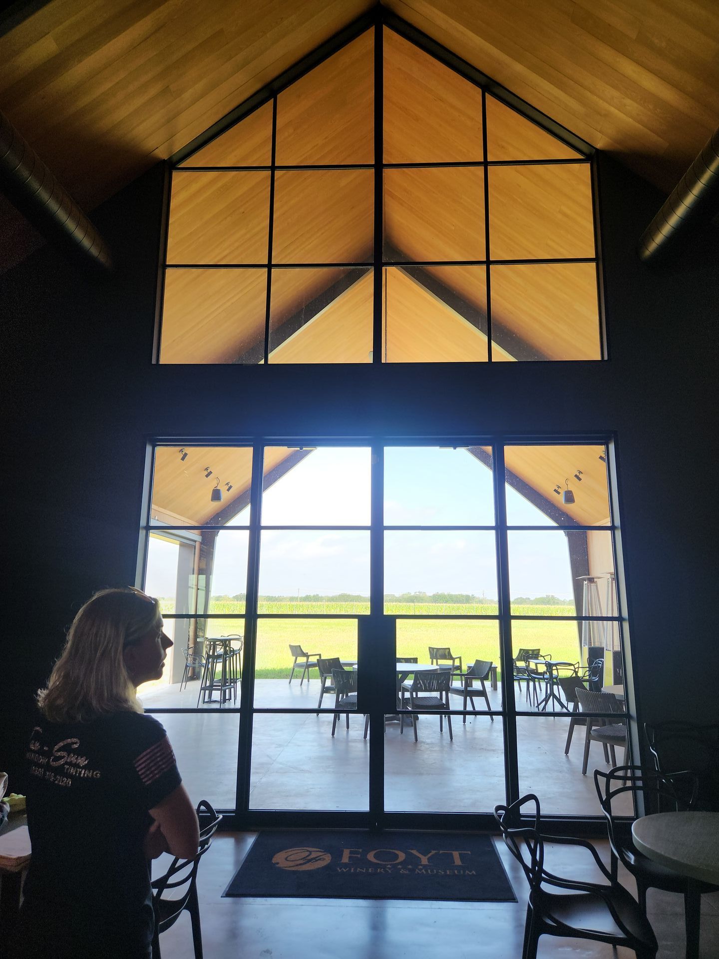 A woman stands in front of a large glass door that says joyt on it