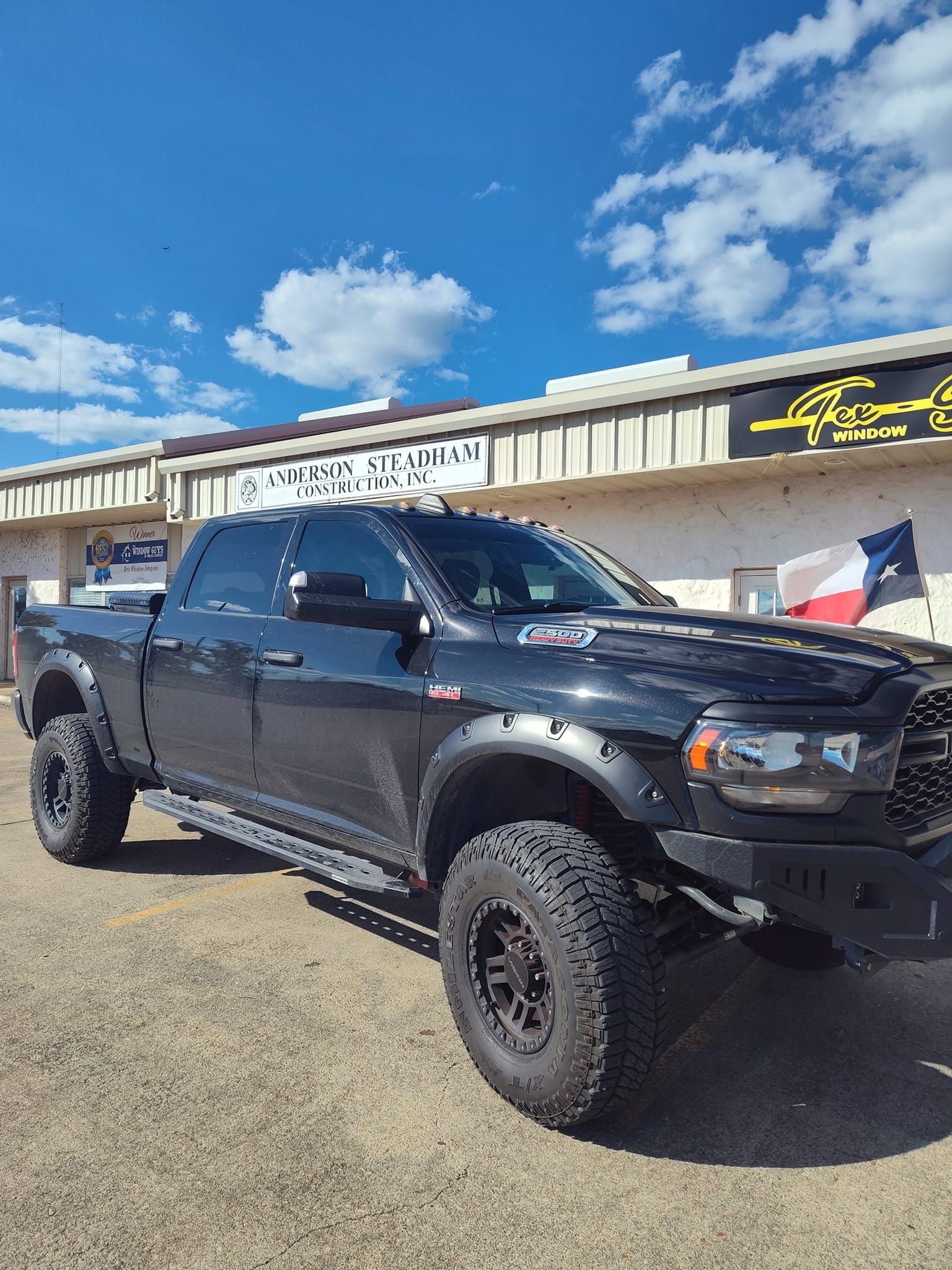 A black truck is parked in front of a building.