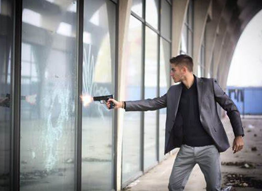 A man shooting the panel glass with ballistic film.