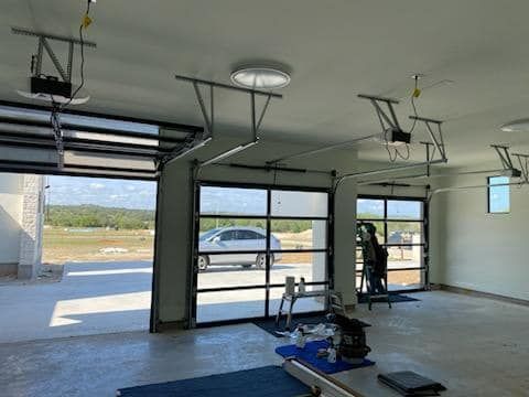 A garage with two garage doors open and a car parked in the driveway.