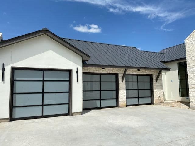 A white house with a gray roof and two garage doors
