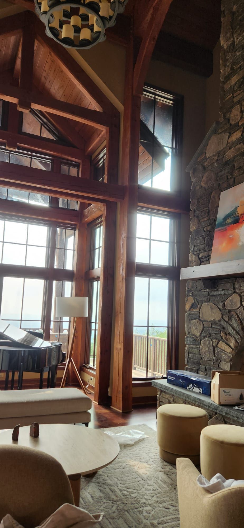 Living room with tall windows, wooden beams, a fireplace, and seating.