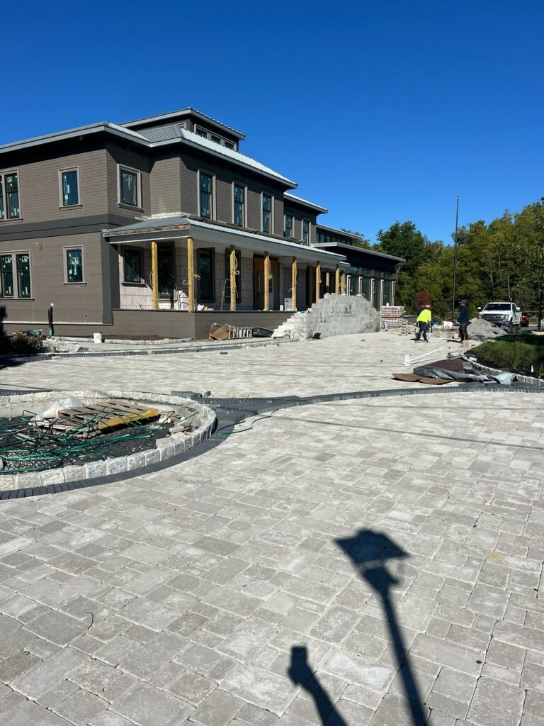 Patio with gazebo, gray pavers, black fence, and light-colored wooden supports.