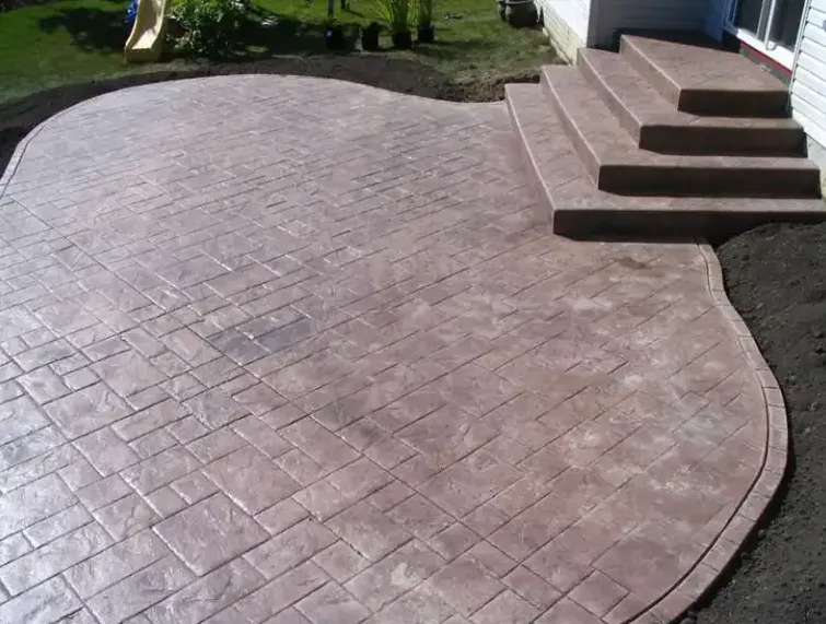 Stamped concrete patio with steps leading to a house; brown brick pattern and edges.