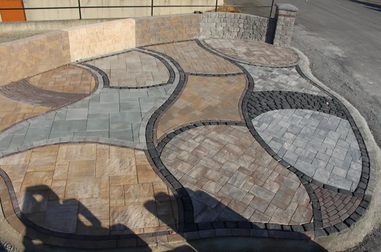 Stone patio with varied patterns and colors, bordered by stone walls.