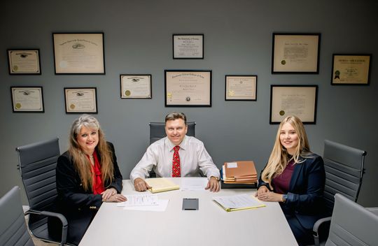 A man and two women are sitting at a table in a conference room.