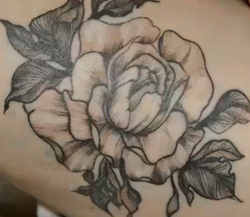 Black-and-gray rose tattoo with detailed petals and leaves on skin