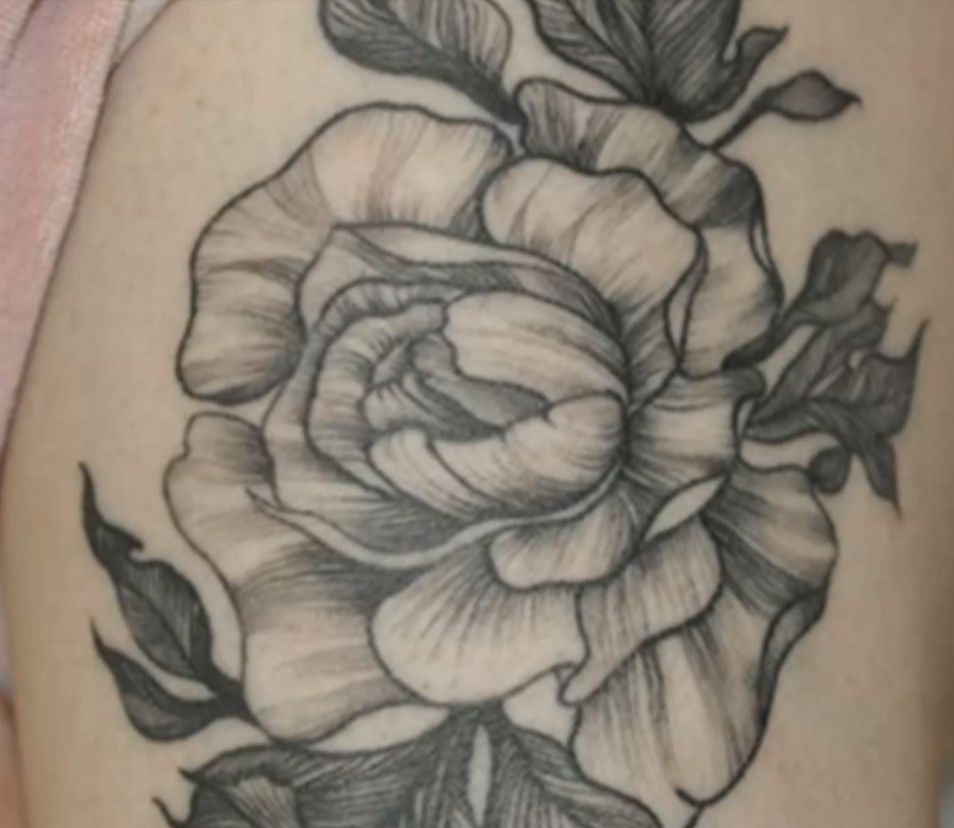 Black-and-gray rose tattoo with leaves on skin