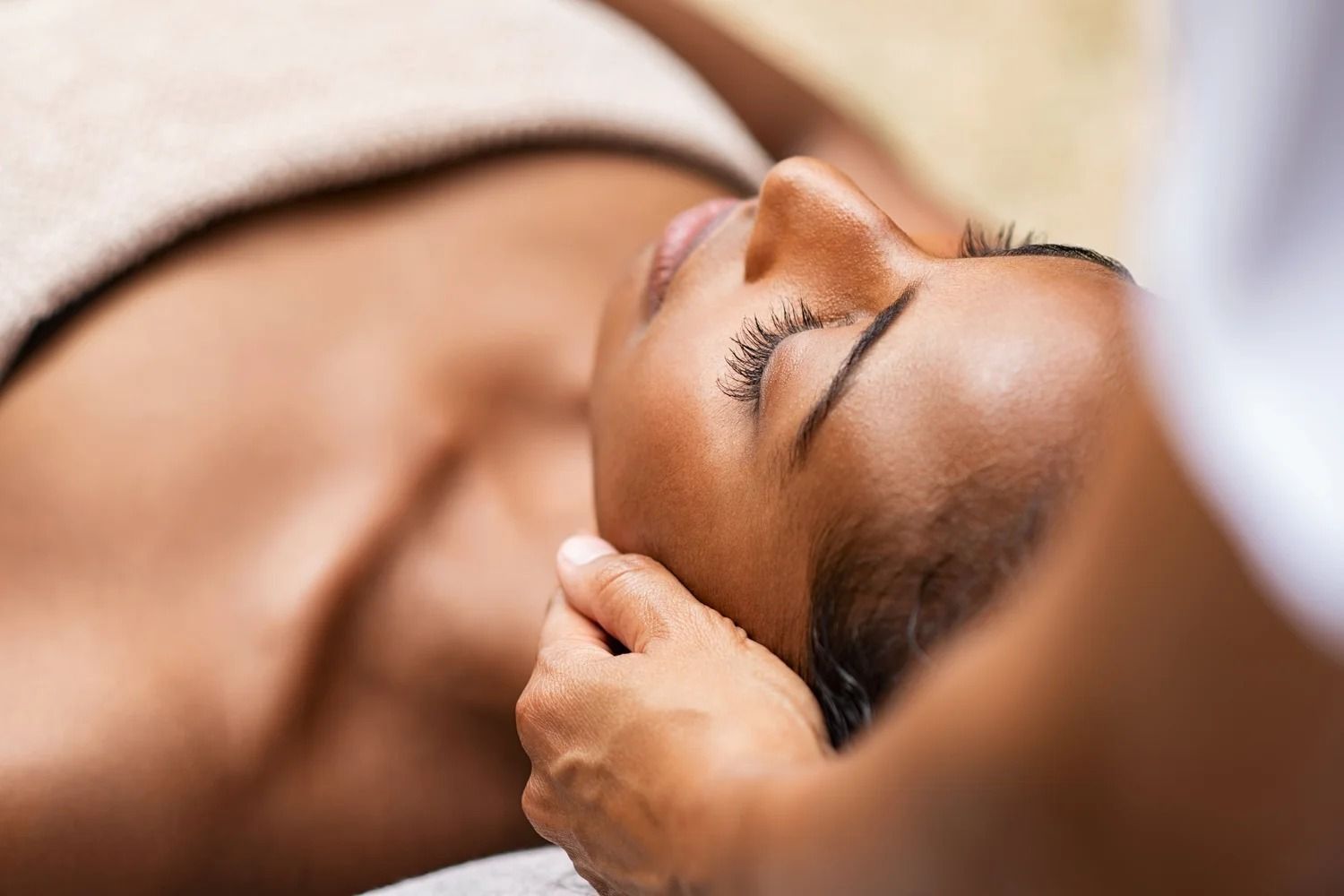Person receiving a head massage. A hand gently touches their head, eyes closed.