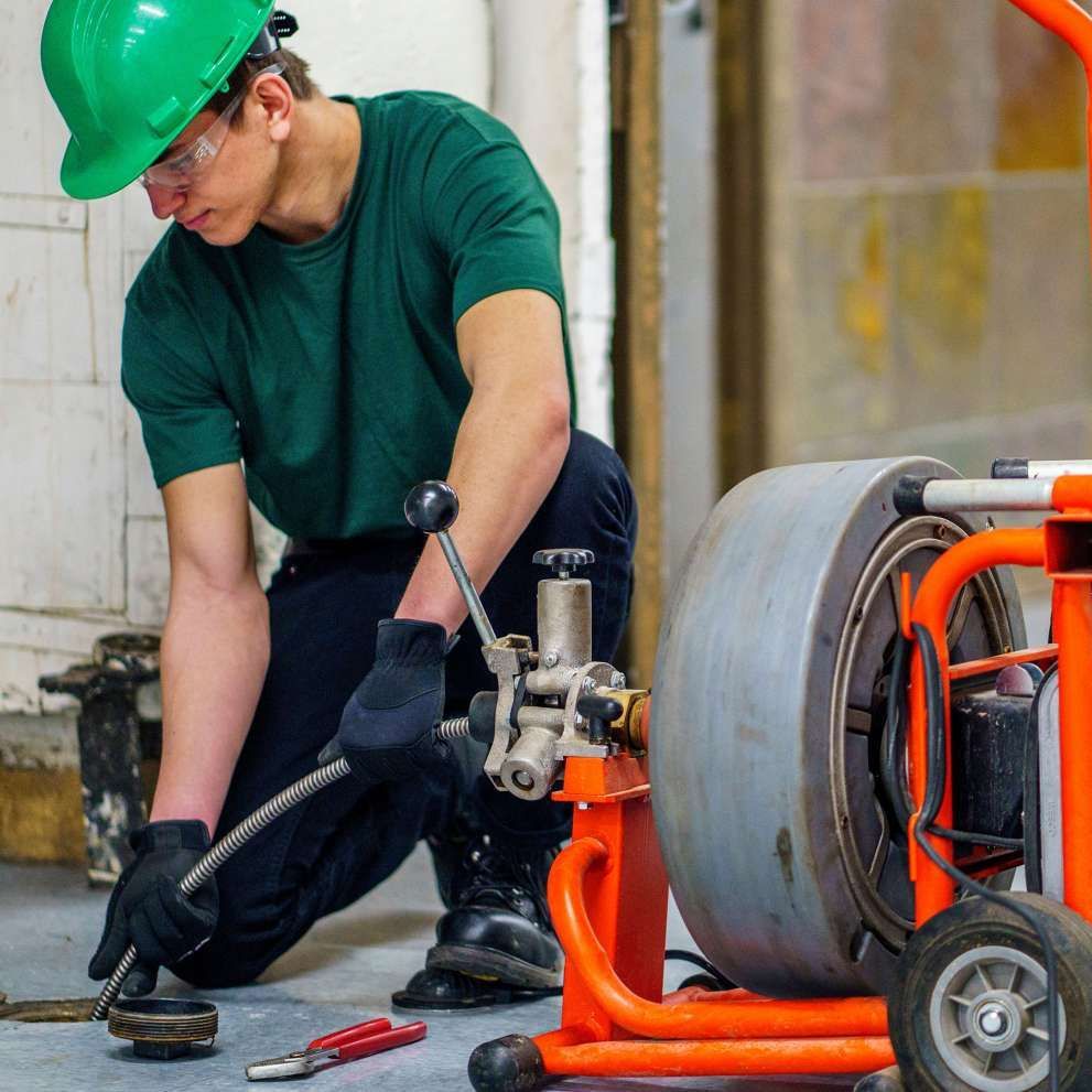 Man unclogging a pipe with a plumbing snake