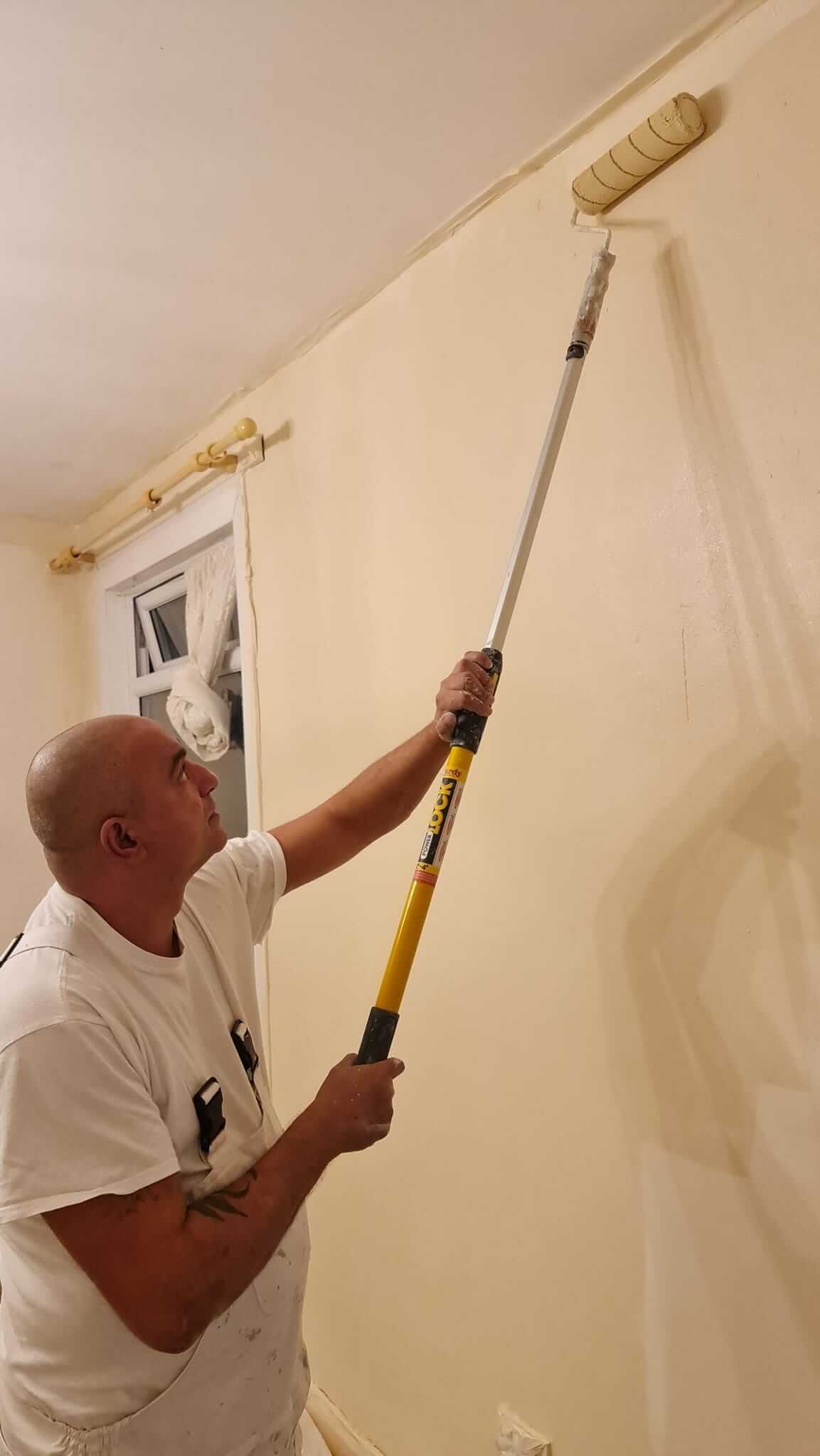Man painting a wall using a roller