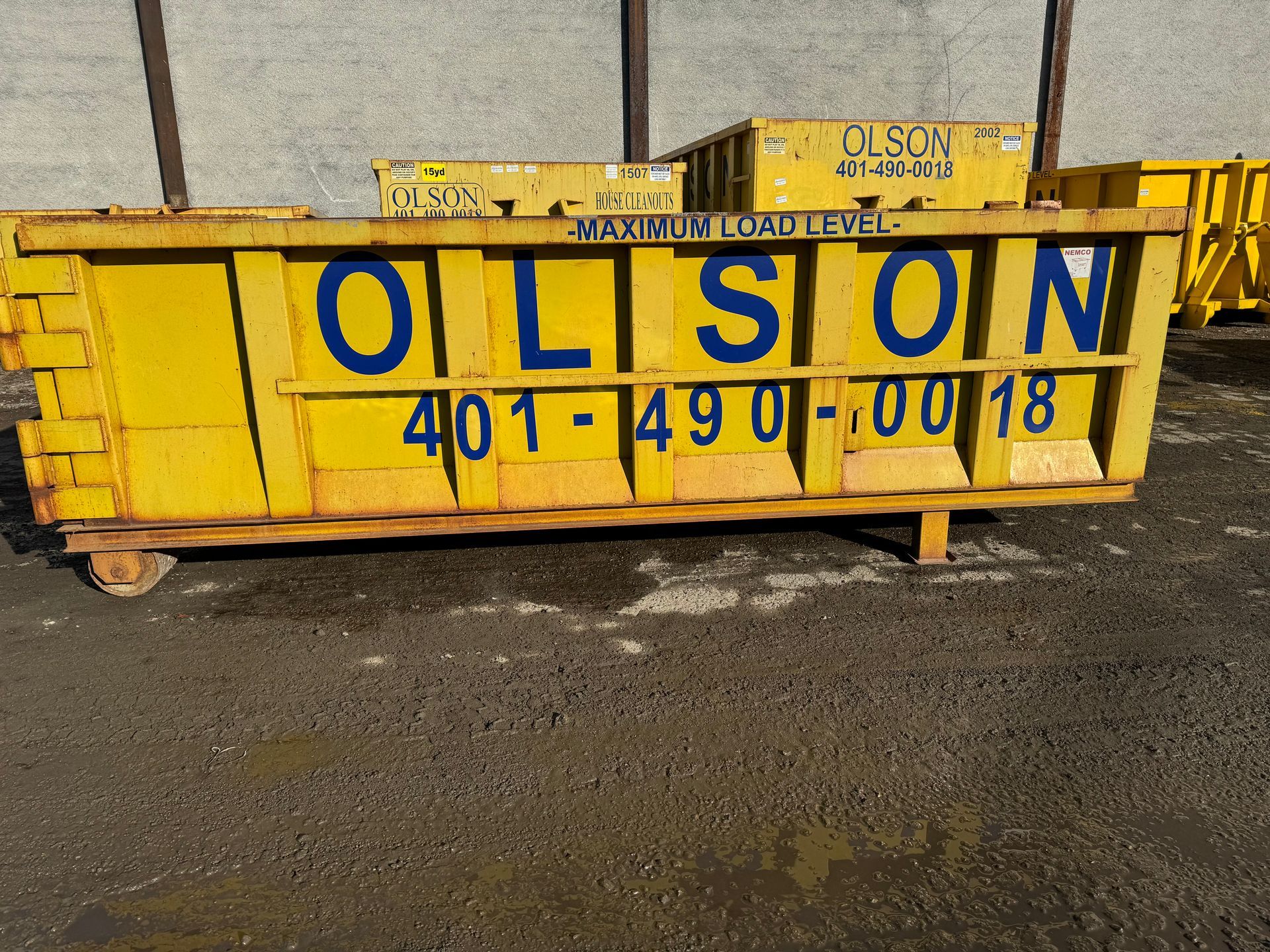 A yellow dumpster that says Olson on it