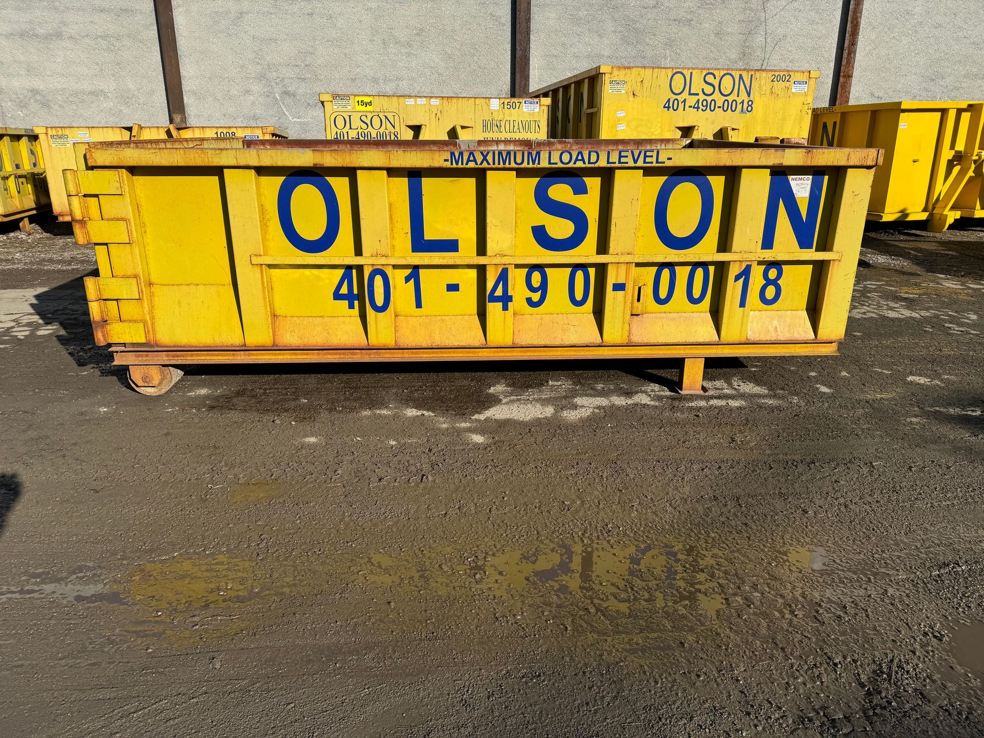 A 10-yard yellow dumpster with the word Olson on it